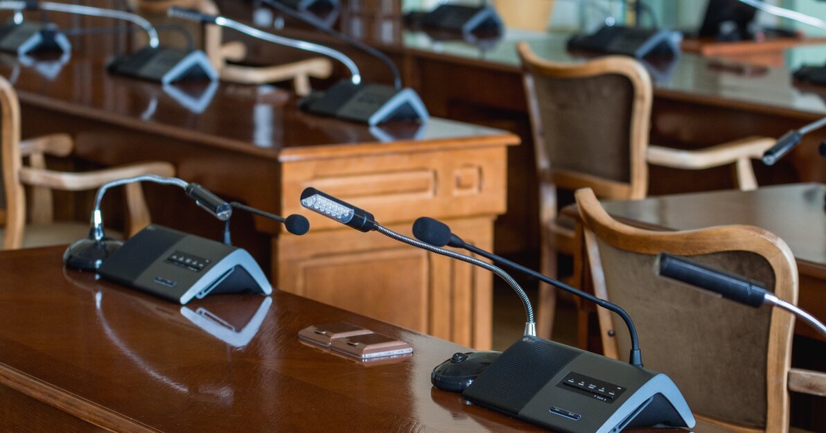 Miejsce obrad Rady Miasta, na pierwszym planie stoły z mikrofonami i przyrządami do głosowania.