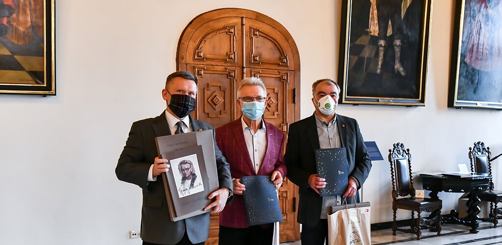 Na zdjęciu od lewej Waldemar Ossowski, dyrektor Muzeum Gdańska, Karol Klukowski oraz Jacek Borzych z egzemplarzem Teki Gdańskiej oraz pakietami Darczyńcy Muzeum Gdańska w Wielkiej Sali Wety Ratusza Głównego Miasta, w tle obrazy i drzwi. 