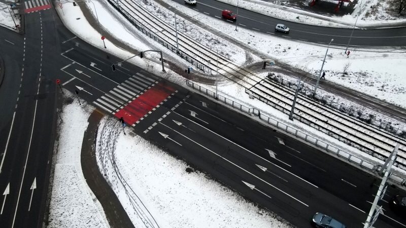 Widok na jezdnię z lotu ptaka, widoczne są znaki nakazu jazdy prostu i prwoskrętu.