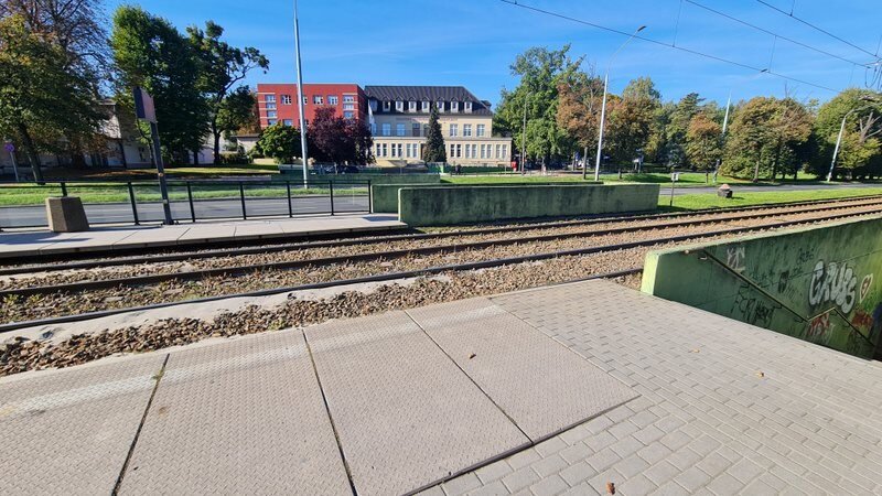 Na pierwszym planie przystanek, na drugim tory tramwajowe, z prawej zejście do tunelu.