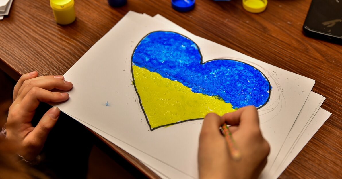 Zdjęcie. Ręce dziecka. Na kartce namalowane serce w kolorach flagi Ukrainy. 