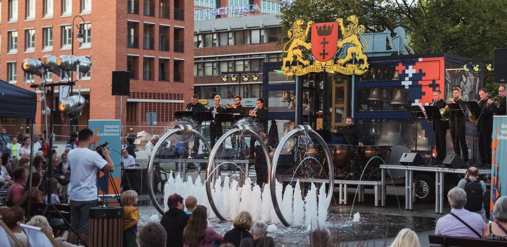 Słuchacze koncertu carillonowego przy skwerze Heweliusza. W tle carillon mobilny "Gdańsk" i zabudowania przy ul. Rajskiej.