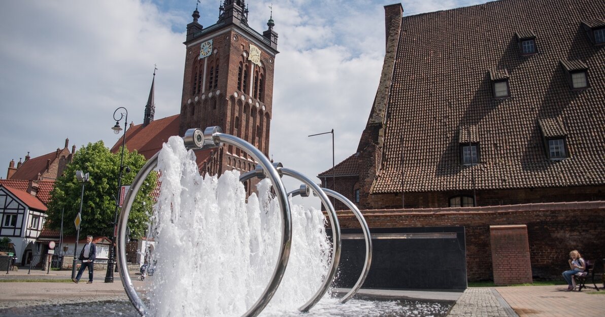 Zdjęcie. Od lewej, Kościół św. Katarzyny i Wielki Młyn. Przed nimi Fontanna Heweliusza. 