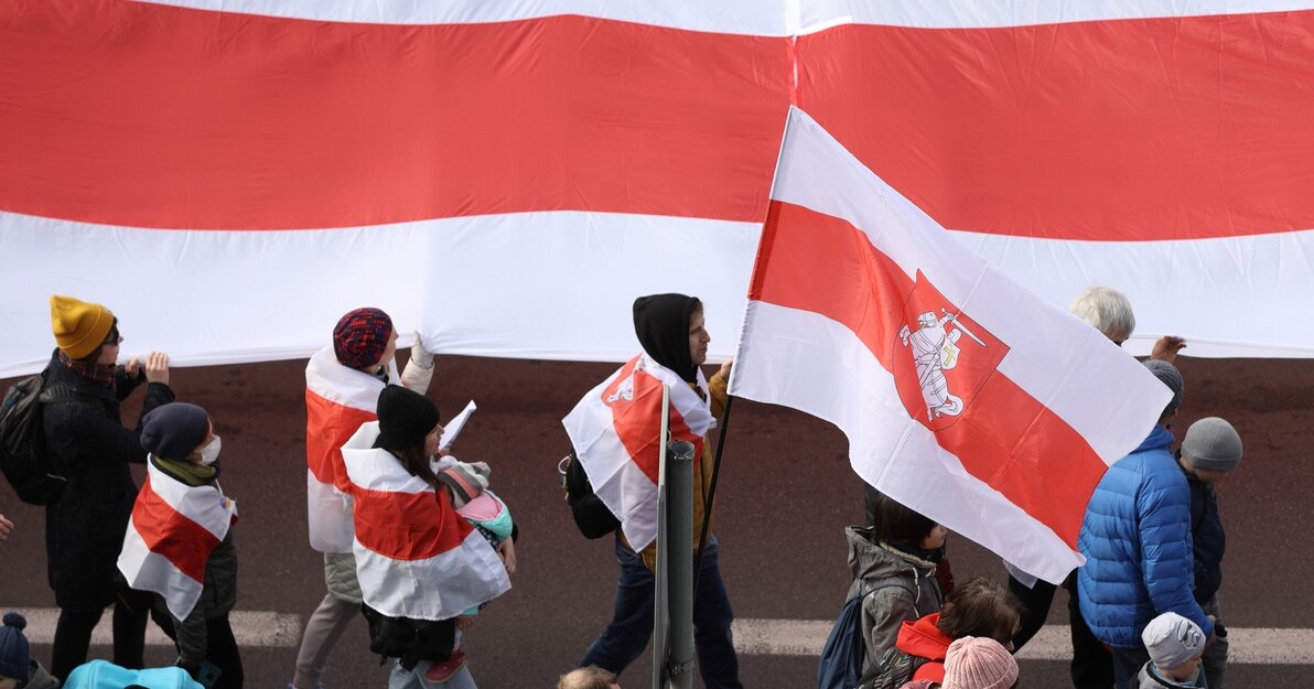 Zdjęcie z marszu ZA WASZĄ I NASZĄ WOLNOŚĆ - solidarnościowy marsz i wiec antywojenny. Osoby na zdjęciu niosą flagi Białorusi. 