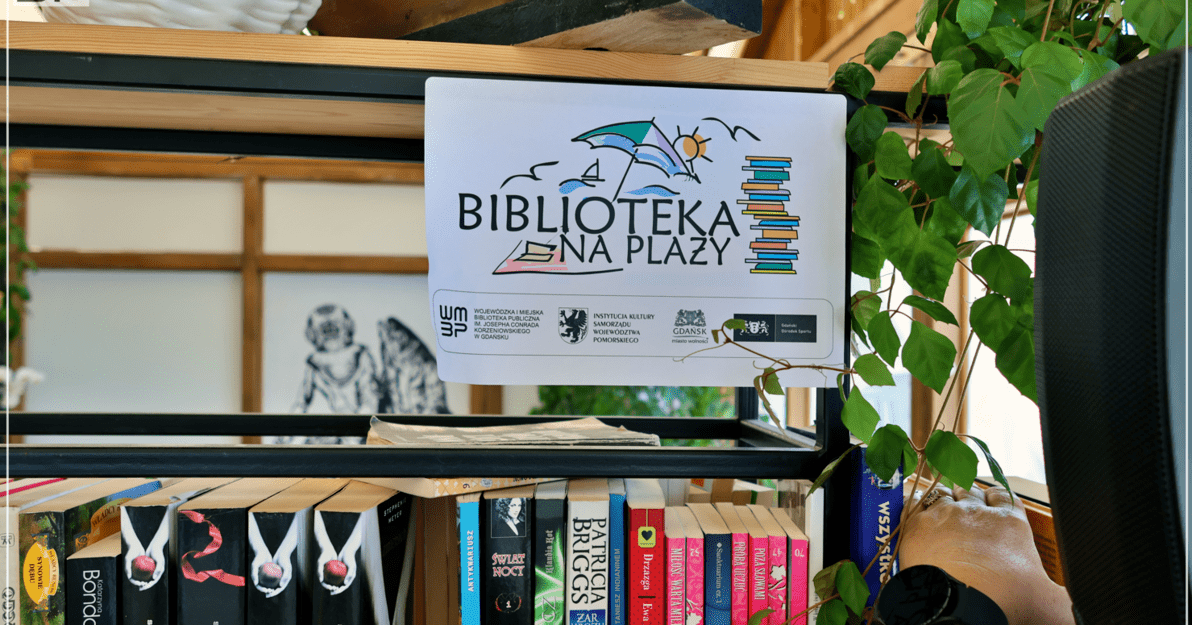 Zdjęcie regału z książkami i oznaczenie, że jest to biblioteczka w ramach projektu Biblioteka na plaży. 
