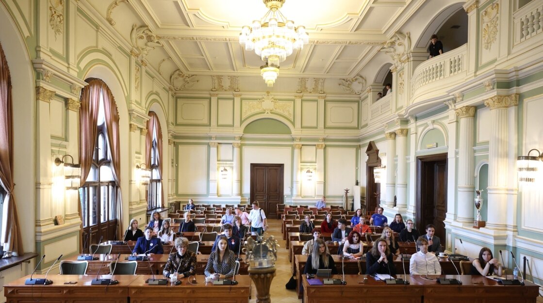 Sala obrad rady miasta Gdańska, widok ogólny od strony prezydium. Radni Młodzieżowej Rady podczas obrad, w ławach za pulpitami do głosowania.