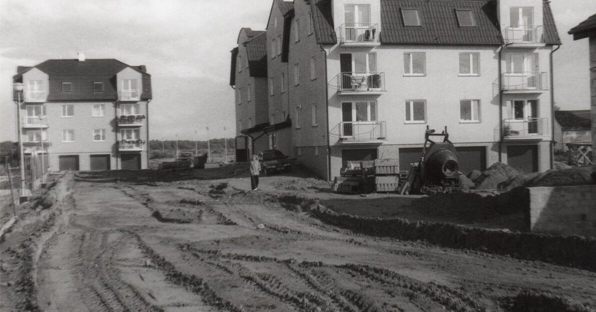 Jedno ze zdjęć przekazanych przez Andrzeja Kowalczyka. Widok na ulicę Borhardta w 1998 roku. Na pierwszym planie droga, w tle dwa budynki mieszkalne. Zdjęcie w odcieniach szarości. 