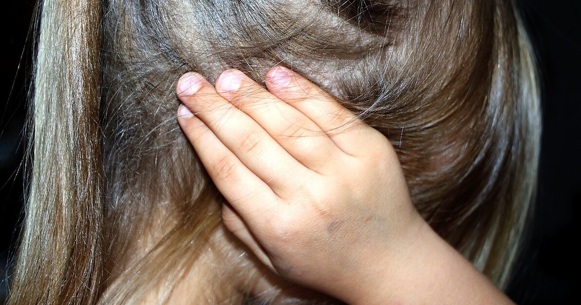 Zdjęcie dziewczynki zasłaniającej uszy dłońmi