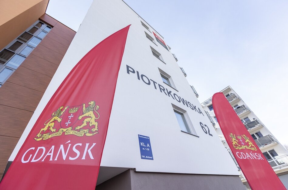 Wejście do budynku przy Piotrkowskiej 62 oraz flagi z herbem Gdańska. 